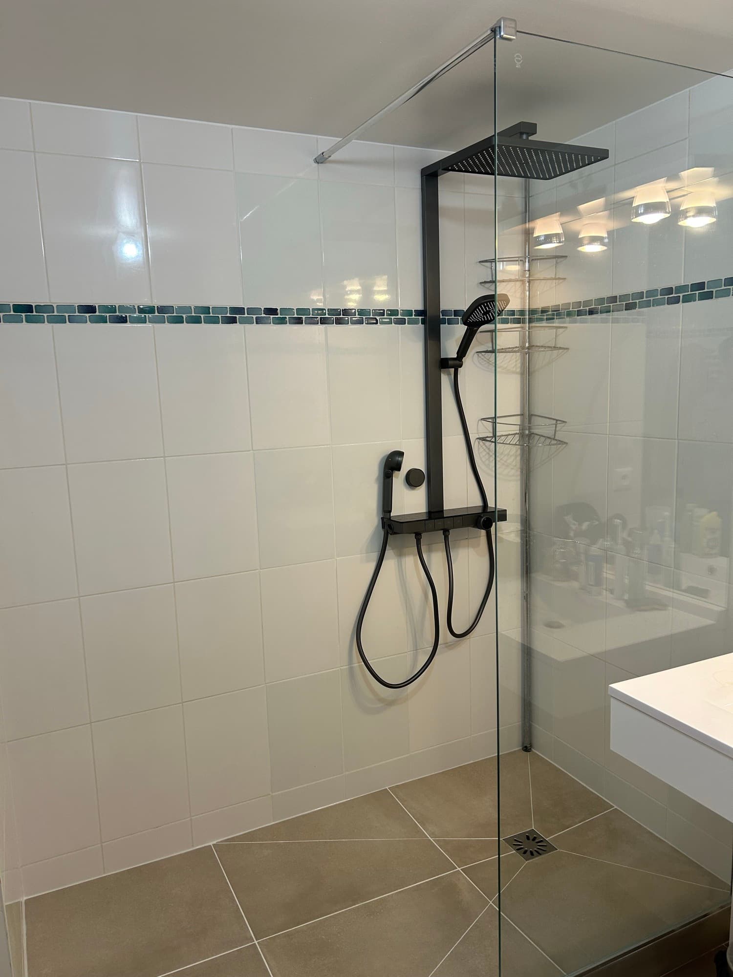 Lognes : douche de plain-pied accessible, receveur carrelé dans la continuité du sol, colonne de douche noire et paroi fixe